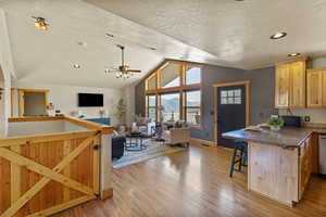 Kitchen with open floor plan, a peninsula, a breakfast bar, a ceiling fan, and a textured ceiling