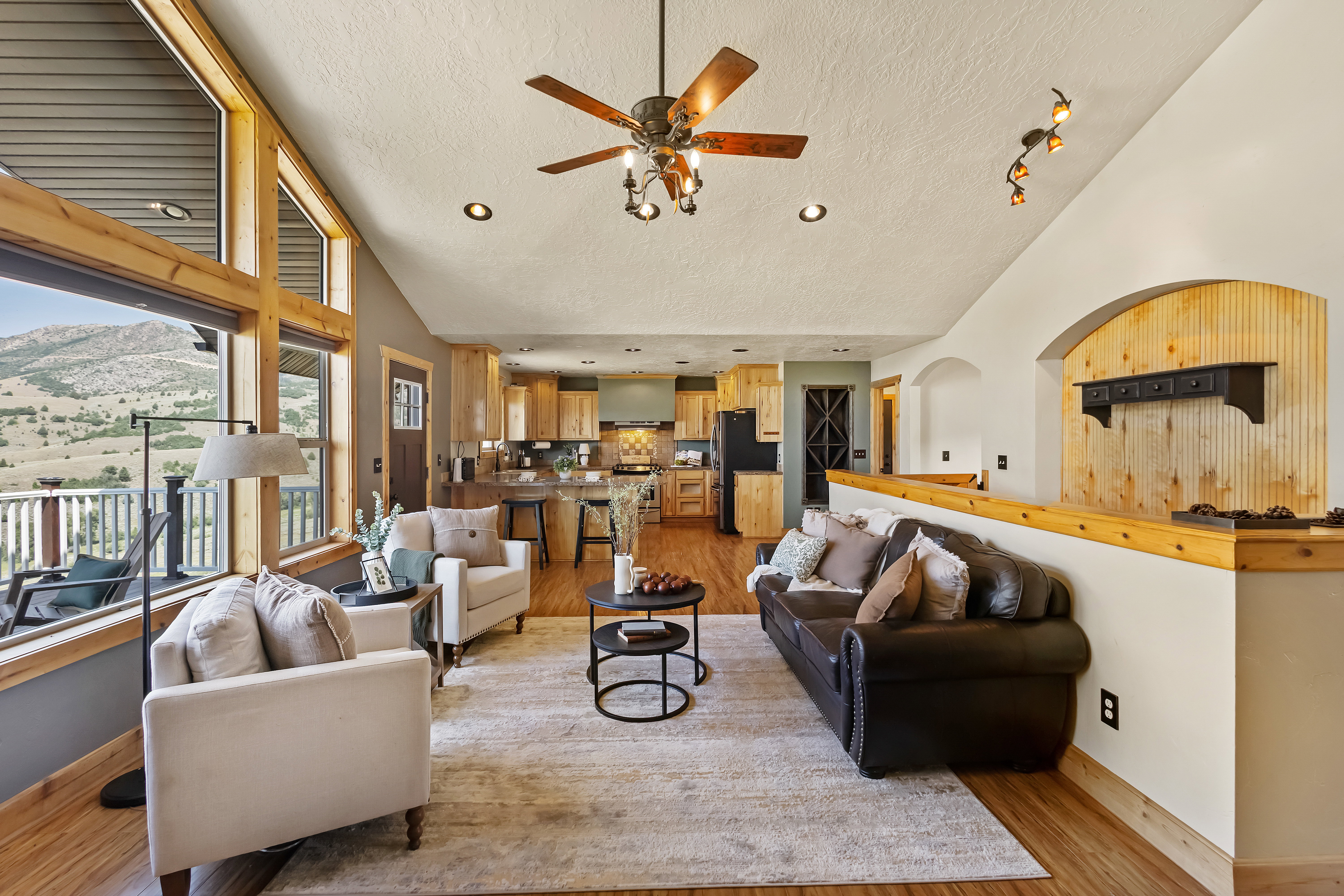 Living room featuring a mountain view, ceiling fan, a high textured ceiling, and light wood finished floors