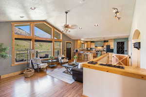 Living area with a textured ceiling, light wood-style floors, a ceiling fan, recessed lighting, and arched walkways