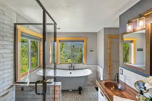 Full bath featuring vanity, a soaking tub, healthy amount of natural light, tile walls, and a textured ceiling