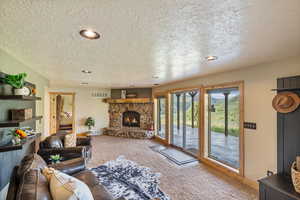 Living room featuring recessed lighting, carpet floors, a textured ceiling, and a fireplace