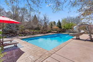 View of swimming pool featuring a water slide, patio surround, an outdoor living space, and a fenced backyard