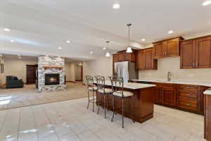 Kitchen with a kitchen breakfast bar, pendant lighting, a kitchen island, open floor plan, and stainless steel fridge