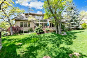 Back of property with a lawn, stucco siding, a chimney, and stone siding