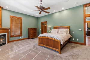 Carpeted bedroom with ceiling fan, a high end fireplace, and recessed lighting