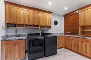 Laundry room featuring cabinet space, light marble finish flooring, washing machine and dryer, and recessed lighting