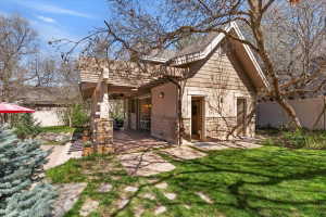 Back of house featuring stone siding, a pergola, a patio, and ceiling fan