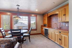 Kitchen featuring hanging light fixtures, beverage cooler, light carpet, a textured ceiling, and backsplash