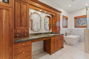 Full bathroom with vanity, light marble finish floors, a freestanding bath, recessed lighting, and wainscoting