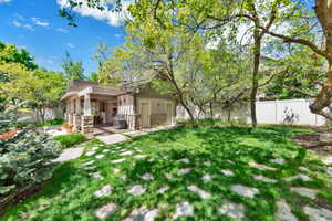 Back of property featuring a fenced backyard, stone siding, and a patio area