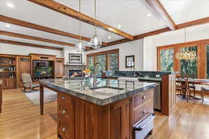Kitchen with a warming drawer, a stone fireplace, stainless steel dishwasher, open floor plan, and a breakfast bar
