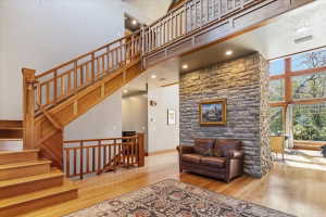 Living room with light wood-style flooring, a high ceiling, and recessed lighting