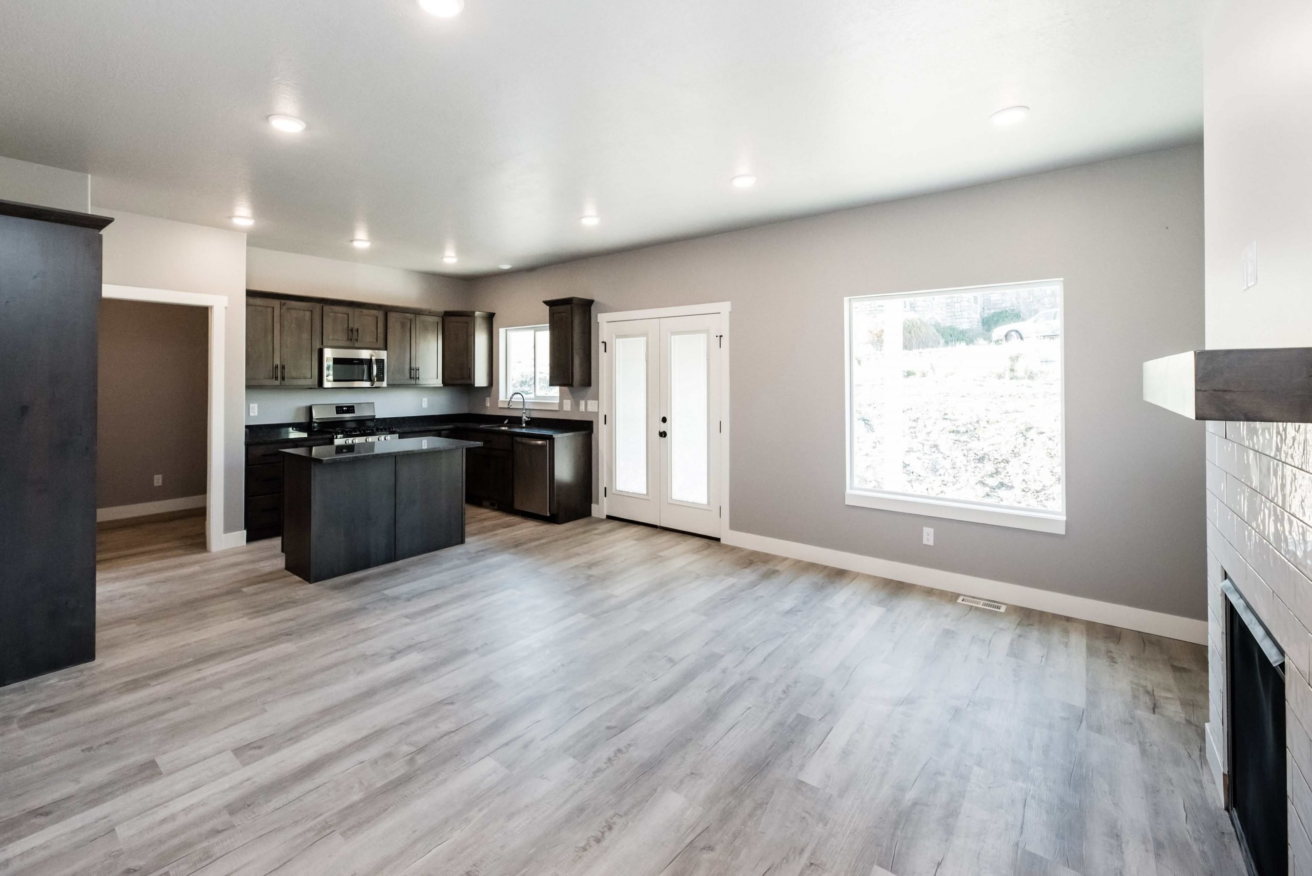 Kitchen with a kitchen island, dark wood finish cabinetry, open floor plan, stainless steel appliances, and dark countertops
