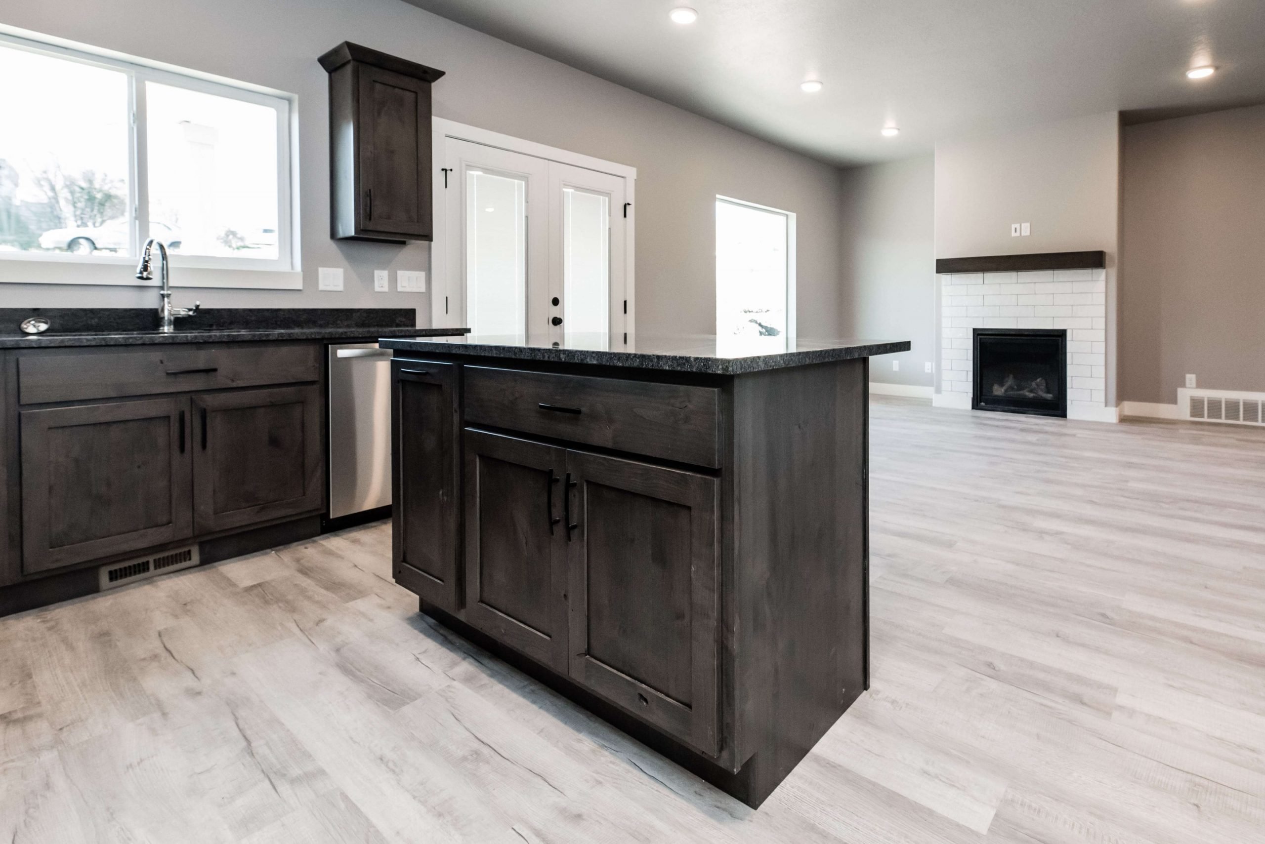 Kitchen featuring dark wood finish cabinets, a kitchen island, a fireplace, light wood-style flooring, and dark stone countertops