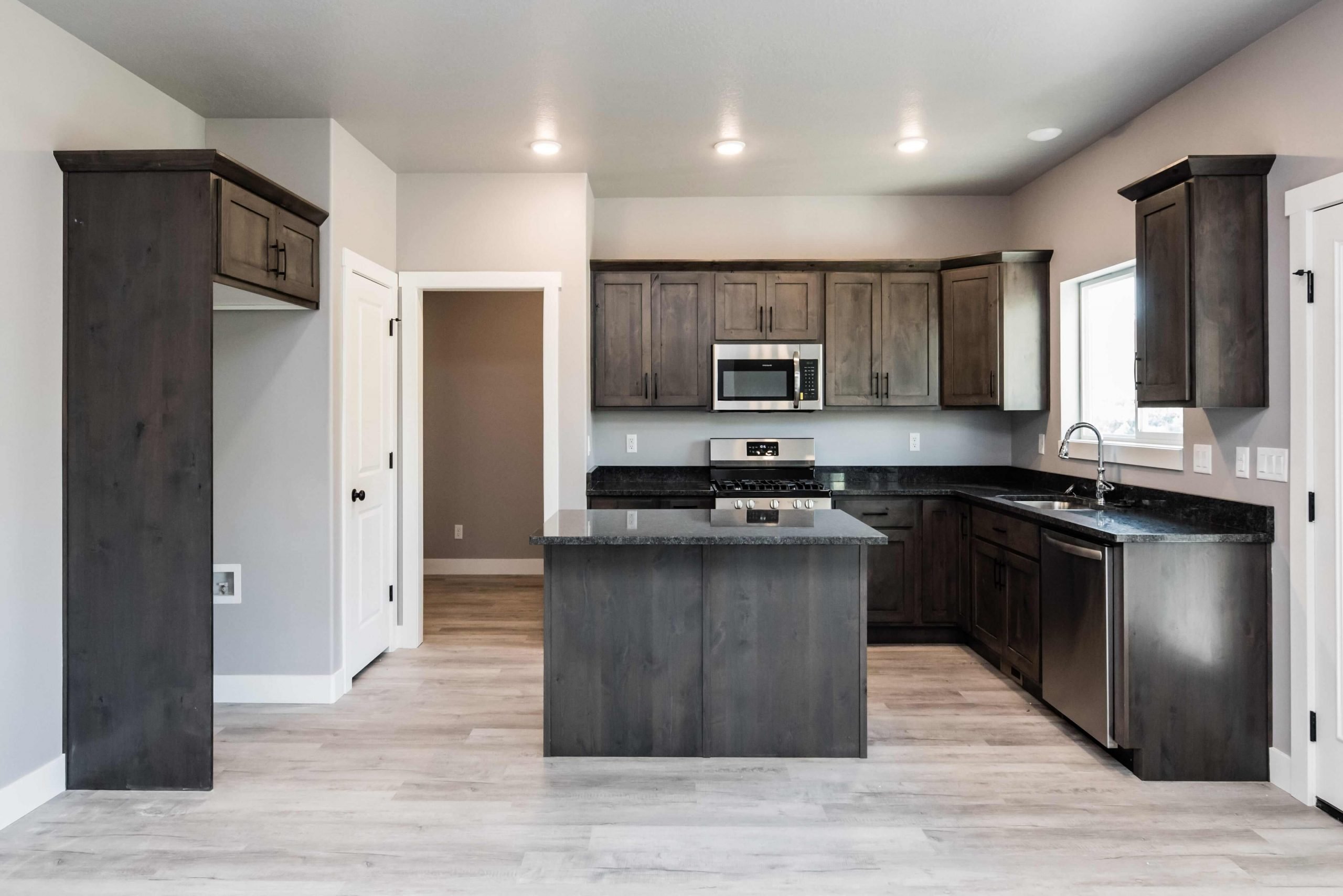 Kitchen featuring dark wood finish cabinets, a center island, stainless steel appliances, and dark stone countertops