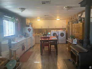 Kitchen with light wood-type flooring, white cabinets, light countertops, and white appliances