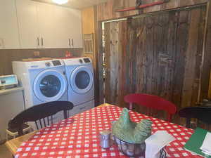 Laundry area featuring wooden walls, washing machine and clothes dryer, and cabinet space