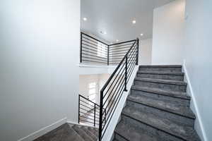 Staircase with a high ceiling, recessed lighting, and carpet