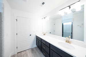 Bathroom with double vanity, light wood-type flooring, and a walk in shower
