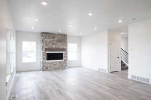 Unfurnished living room with light wood-style flooring, a fireplace, and recessed lighting