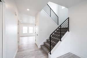 Stairs featuring wood finished floors and recessed lighting