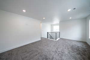 Empty room featuring dark colored carpet and recessed lighting