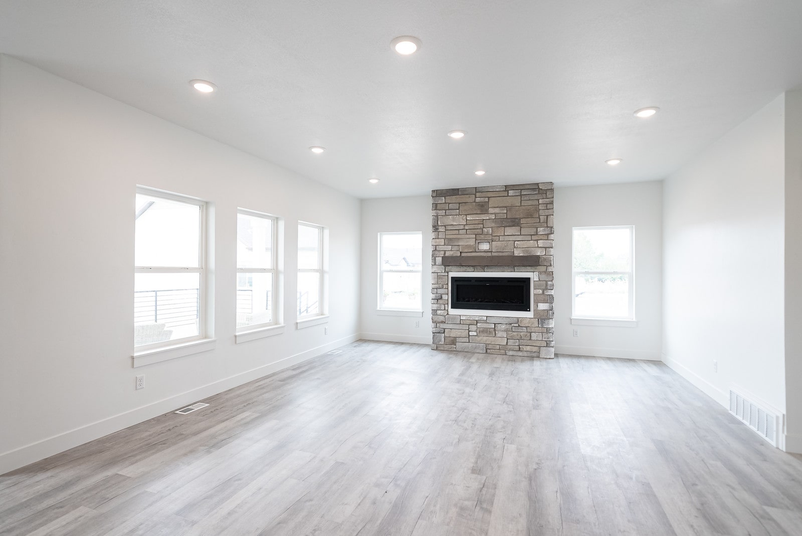 Unfurnished living room featuring a stone fireplace, light wood-style flooring, and recessed lighting