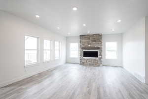 Unfurnished living room featuring a stone fireplace, light wood-style flooring, and recessed lighting