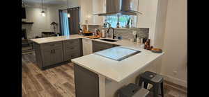 Two tone kitchen with a peninsula, a breakfast bar, range hood, a fireplace, and dual tone cabinetry