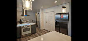 Kitchen with stainless steel appliances, light countertops, dark wood-type flooring, island range hood, and a textured ceiling