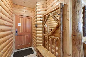 Entryway with log walls and light tile patterned floors