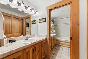 Bathroom featuring vanity, shower / bath combo with shower curtain, and light tile patterned floors