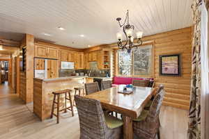 Dining room with light wood finished floors, suspended lighting, and wood ceiling