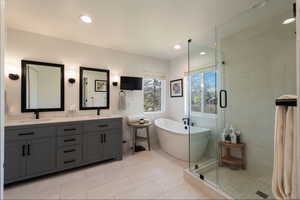 Bathroom with double vanity, a soaking tub, a shower stall, light tile patterned floors, and recessed lighting
