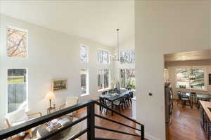 Hall featuring hanging lights, dark wood-type flooring, and lofted ceiling