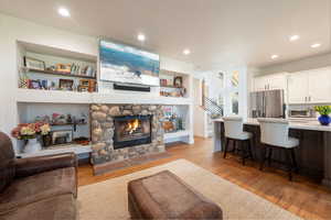 Living area with light wood-style flooring, a fireplace, built in shelves, and recessed lighting