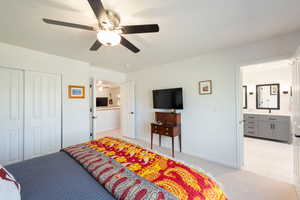 Bedroom featuring light carpet, connected bathroom, a ceiling fan, a closet, and light tile patterned floors
