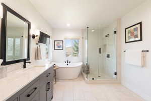 Full bath with vanity, a shower stall, a freestanding tub, light tile patterned floors, and recessed lighting