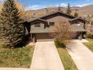 View of front of property with concrete driveway, a chimney, an attached garage, a mountain view, and a shingled roof