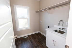 Laundry area with washer hookup, dark wood finished floors, and cabinet space