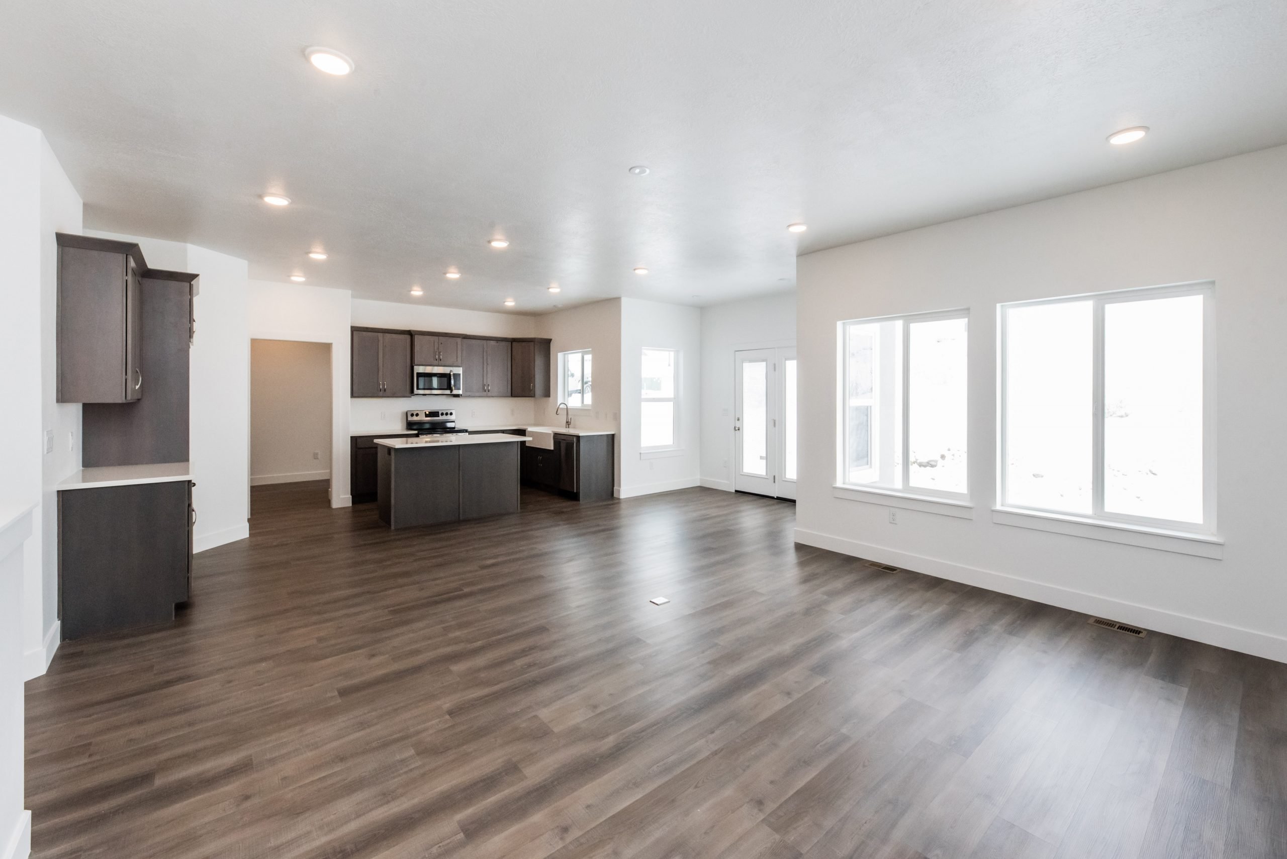 Kitchen with open floor plan, a center island, dark wood finish cabinets, light countertops, and dark wood-style floors