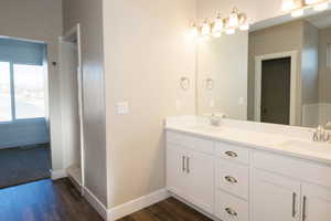 Full bath featuring double vanity and dark wood finished floors