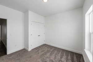 Unfurnished bedroom with dark carpet and a closet