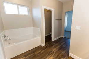 Bathroom featuring a garden tub and dark wood-style flooring