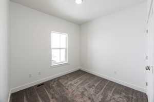 Unfurnished room with baseboards and dark colored carpet