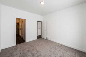 Unfurnished bedroom with dark colored carpet and baseboards