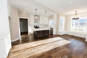 Kitchen with suspended lighting, lofted ceiling, a center island, stainless steel appliances, and dark wood finished floors