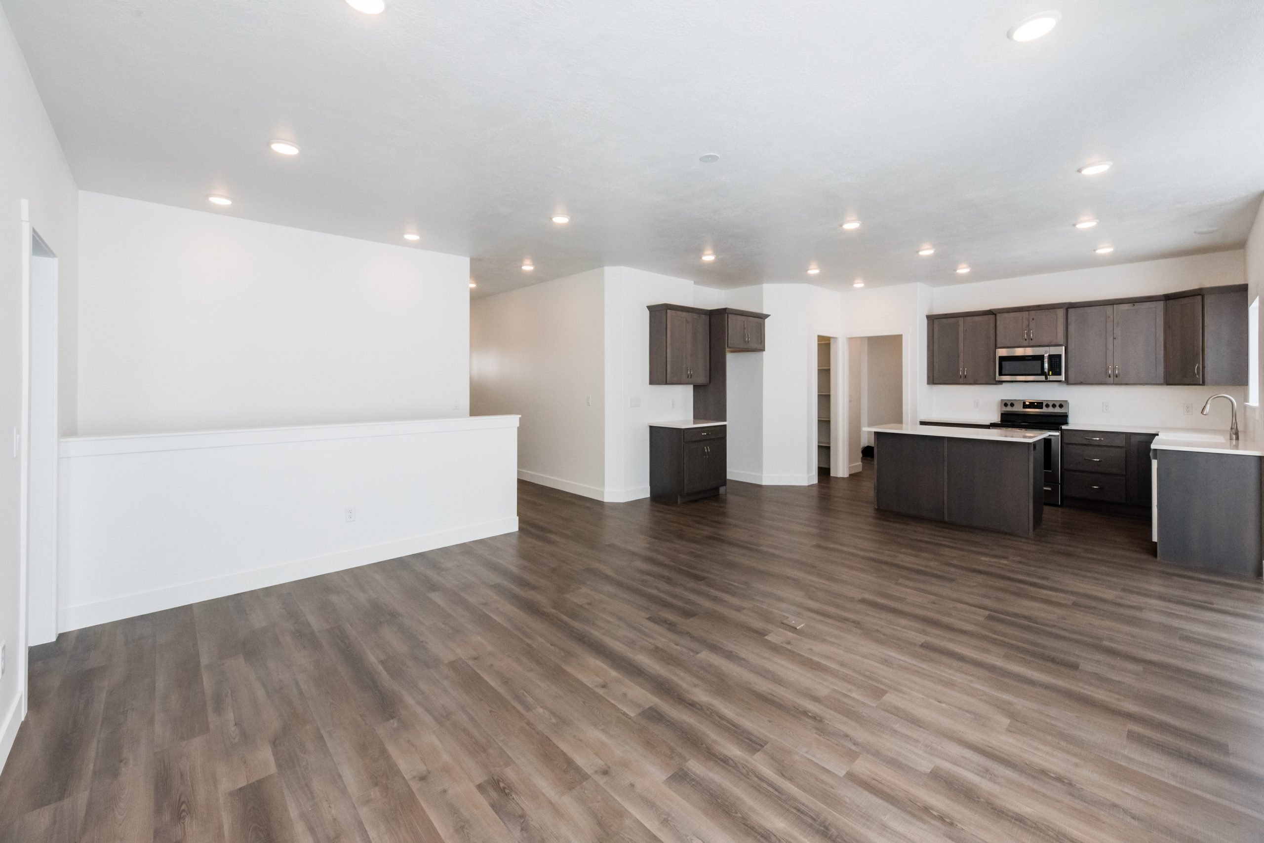 Kitchen with dark wood finish cabinetry, stainless steel appliances, a kitchen island, light countertops, and dark wood finished floors