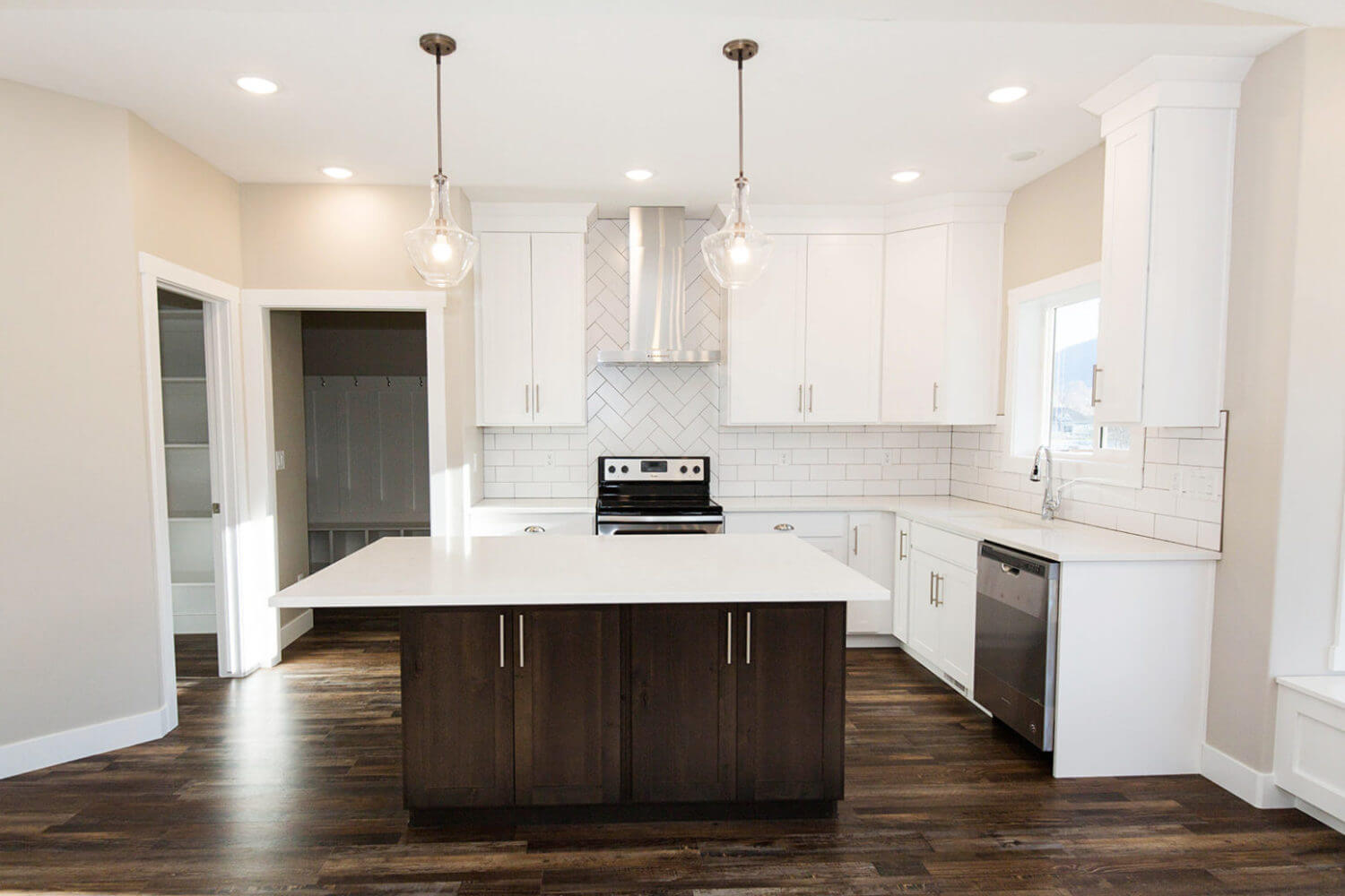 Two tone kitchen featuring stainless steel appliances, dark wood finished floors, dual tone cabinets, pendant lighting, and a kitchen island