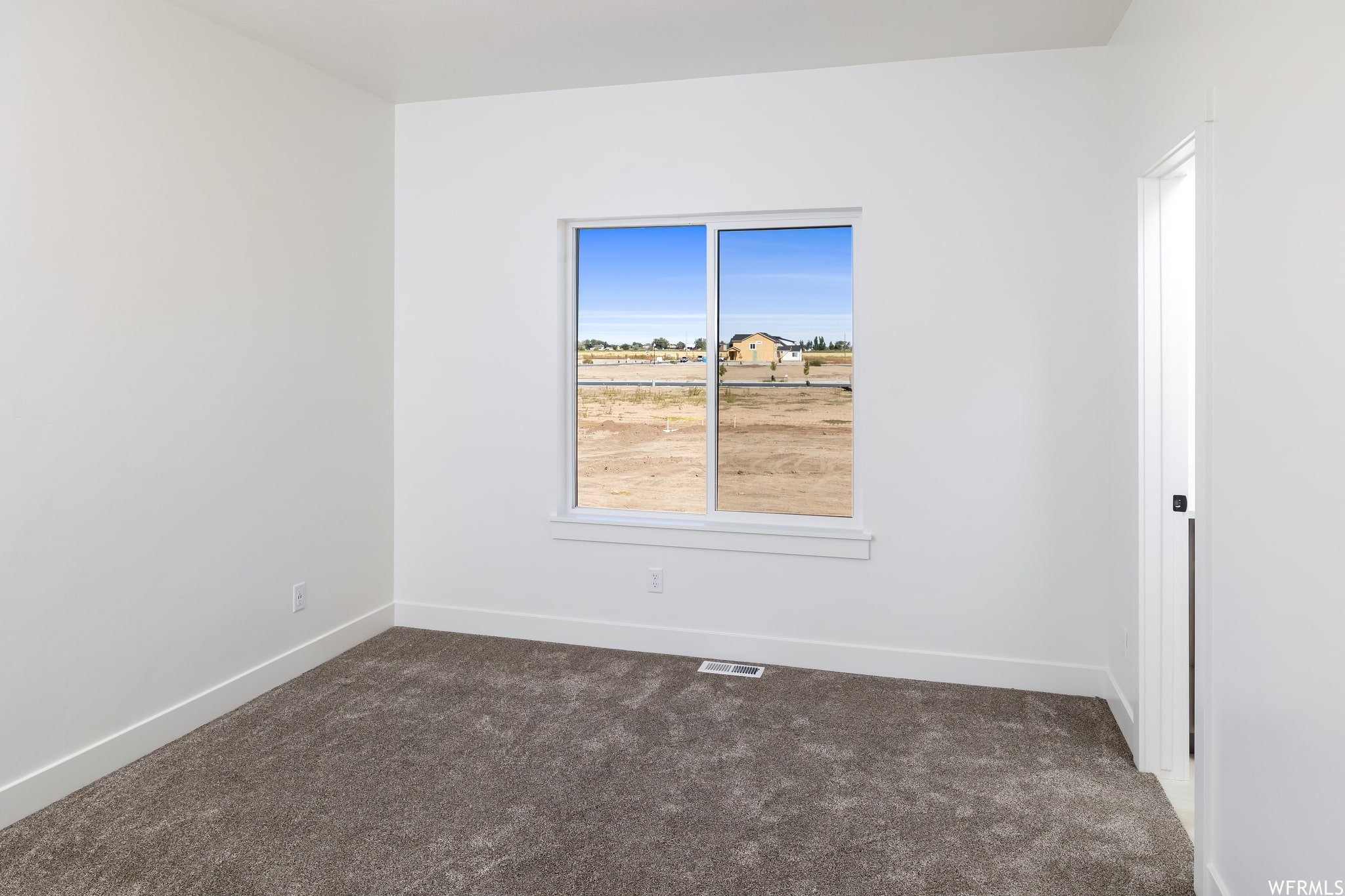 Unfurnished room featuring dark carpet and baseboards